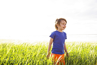 Boy (4-5) standing in grass and looking away, Colorado, USA