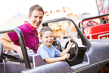 Father with son (4-5) driving toy car in amusement park, USA, Utah, Salt Lake City 