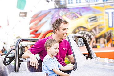 Father with son (4-5) driving toy car in amusement park, USA, Utah, Salt Lake City 