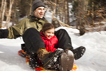 Young man sledding with girl (2-3), USA, Utah, Highland