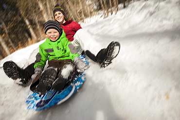 Young woman sledding with boy (4-5), USA, Utah, Highland