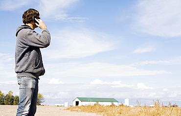 Farmer in field using cell phone, Colorado, USA