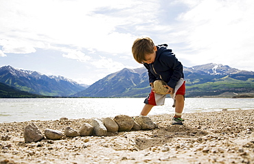 Boy (2-3) with rocks on beach, Colorado, USA