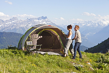 Switzerland, Leysin, Hikers pitching tent on meadow, Switzerland, Leysin