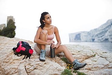 France, Marseille, Female hiker resting on rocky beach, France, Marseille