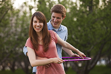 Young couple using plastic hoop in orchard