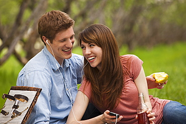 Young couple with mp3 player in orchard