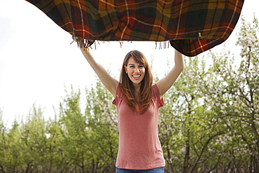 Young woman holding blanket in orchard