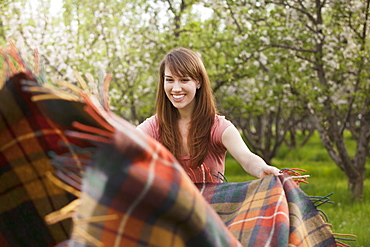 Young woman holding blanket in orchard