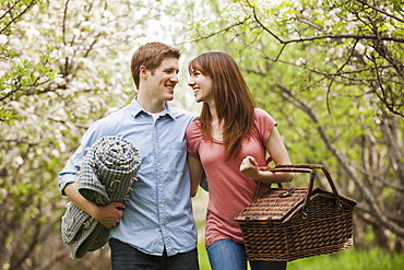 Young couple with picnic basket in orchard