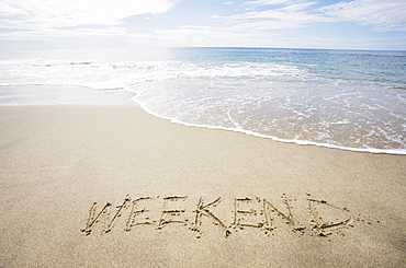 USA, Massachusetts, Word "weekend" drawn on sandy beach