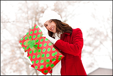 USA, Utah, Lehi, Portrait of young woman holding Christmas gift outdoors