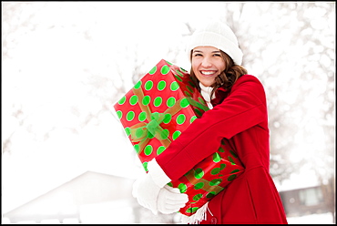 USA, Utah, Lehi, Portrait of young woman hugging Christmas gift outdoors