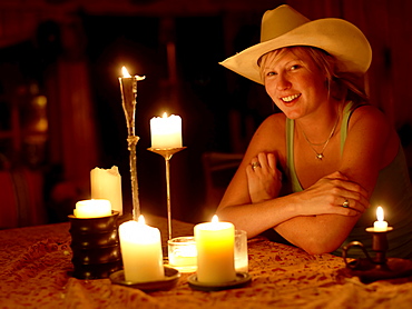 USA, Colorado, Portrait of cowgirl sitting at table with candles