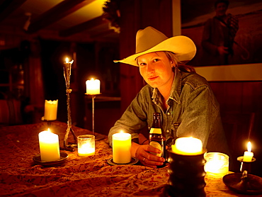 USA, Colorado, Portrait of cowgirl sitting at table with candles