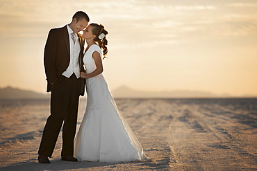 Bride and groom embracing in desert