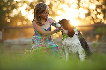 Girl (8-9) stroking dog in field