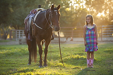 Girl (8-9) standing with horse in paddock