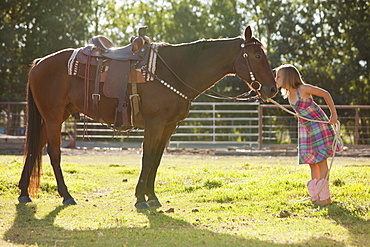 Cowgirl (8-9) kissing horse in ranch