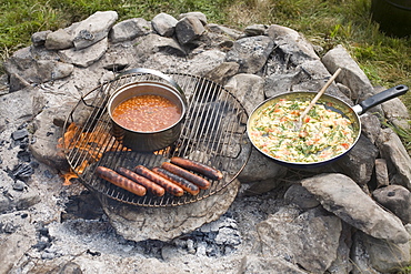 Grilled sausages and beans on campfire