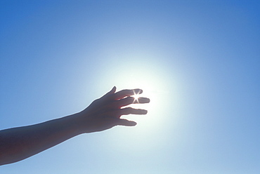 Silhouette of woman's hand against sky