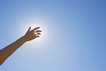 Hand in front of a sun flare in the sky