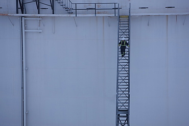 Worker walking down stairs on an oil tank