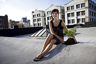 Woman sitting on rooftop beside aspen sapling