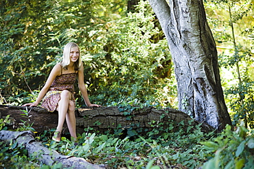 Young woman sitting on log