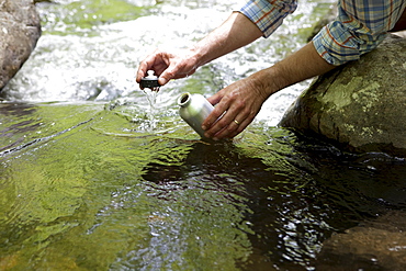 A man with a reusable water bottle in the woods