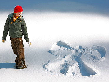 Woman looking at snow angel shape