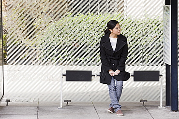 Young woman waiting at bus stop, San Francisco, California, USA