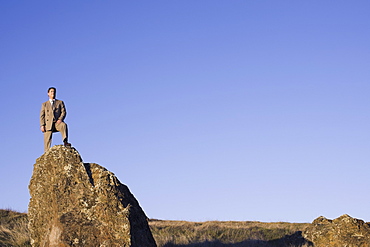 Businessman standing on rock