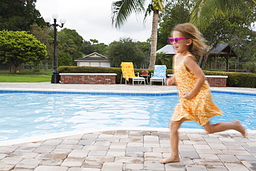 Girl running beside swimming pool