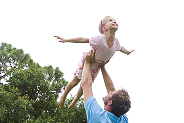 Father lifting daughter in backyard