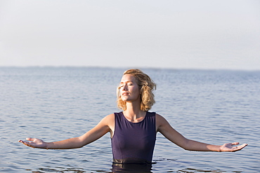 Beautiful woman standing in lake with arms outstretched