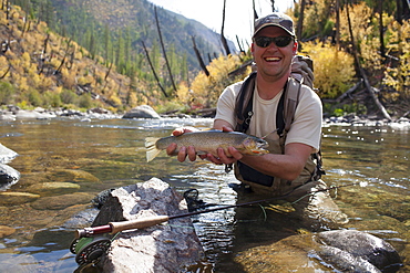 Fisherman showing fresh trout, North Fork Blackfoot River, Montana, USA