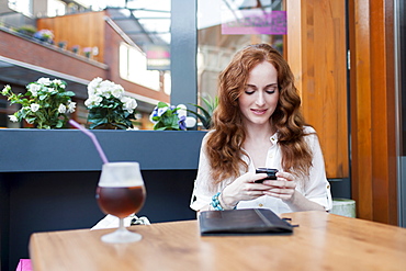 Elegant woman in cafe using mobile phone, Goirle