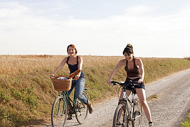 France, Picardie, Albert, Young women on bikes on country road, France, Picardie, Albert