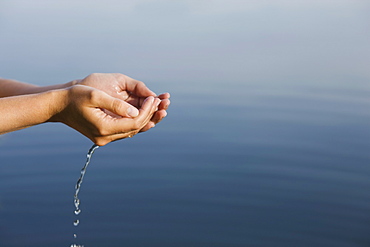 Cupped hands holding water from lake