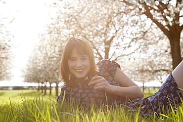 Belgium, Sint-Truiden, Portrait of young woman in spring orchard, Belgium, Sint-Truiden