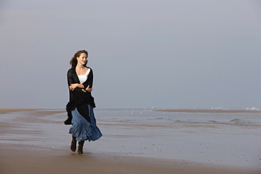 France, Pas-de-Calais, Escalles, Young woman strolling on empty beach, France, Pas-de-Calais, Escalles