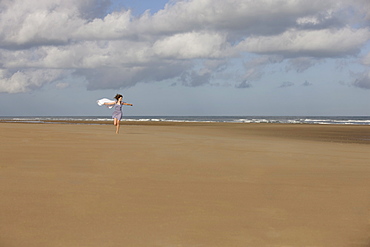 France, Pas-de-Calais, Escalles, Young woman strolling on empty beach, France, Pas-de-Calais, Escalles