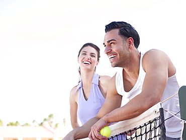 Smiling couple standing near tennis net