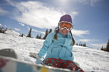 USA, Colorado, Telluride, Girl (10-11) posing with snowboard in winter scenery 