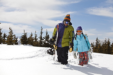 USA, Colorado, Telluride, Father and daughter (10-11) posing with snowboards in winter scenery