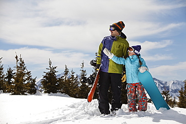 USA, Colorado, Telluride, Father and daughter (10-11) standing with snowboards in winter scenery