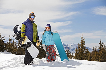 USA, Colorado, Telluride, Father and daughter (10-11) posing with snowboards in winter scenery