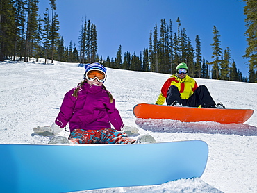 USA, Colorado, Telluride, Father and daughter (10-11) posing with snowboards in winter scenery