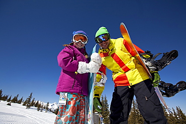 USA, Colorado, Telluride, Father and daughter (10-11) posing with snowboards in winter scenery